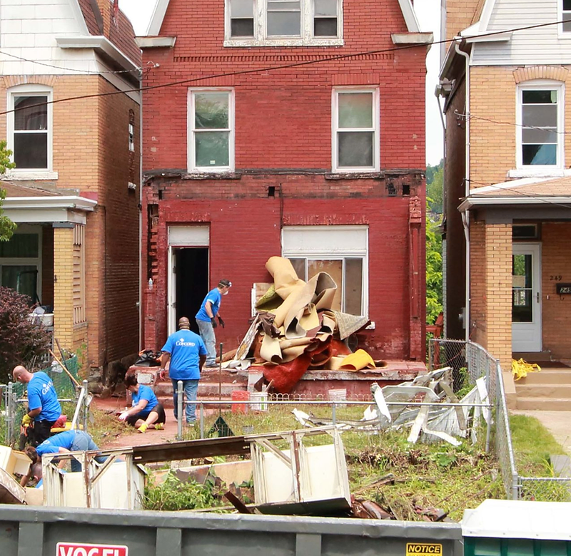 Volunteers clearing the yard of a row house undergoing repair