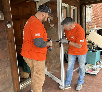 Volunteers installing a storm door on a front porch