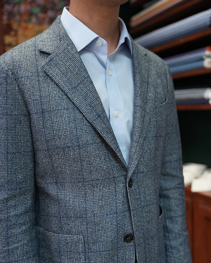 A grey and blue windowpane plaid sport jacket worn over a light blue shirt
