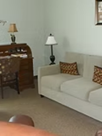Furnished counseling office with a sofa, roll-top desk, and framed art at Oak Brook Counseling & Wellness.