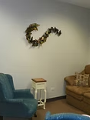 Furnished therapy office with a brown sofa, teal armchair, and wall art at Oak Brook Counseling & Wellness.