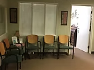 Office waiting room with sage-green walls, botanical art, and upholstered waiting chairs at Oak Brook Counseling & Wellness.