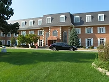 Exterior of the Oak Brook Counseling & Wellness office building, a red brick two-story building with a manicured lawn and trees.