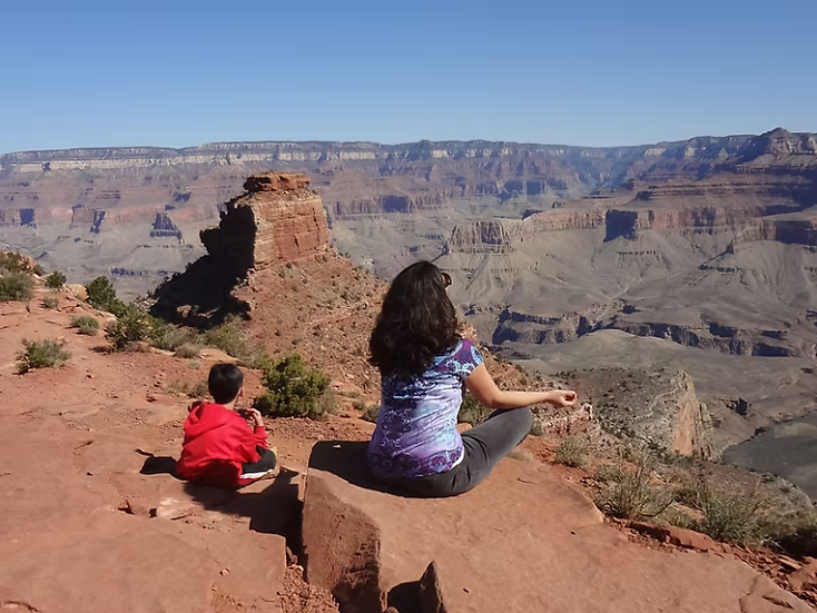 Adult and child sitting together overlooking the Grand Canyon