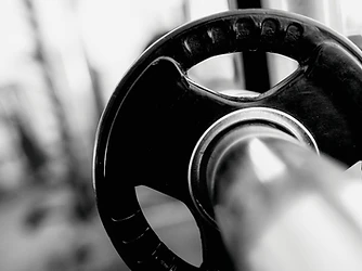 Barbell loaded with weight plates in an empty gym, selective focus