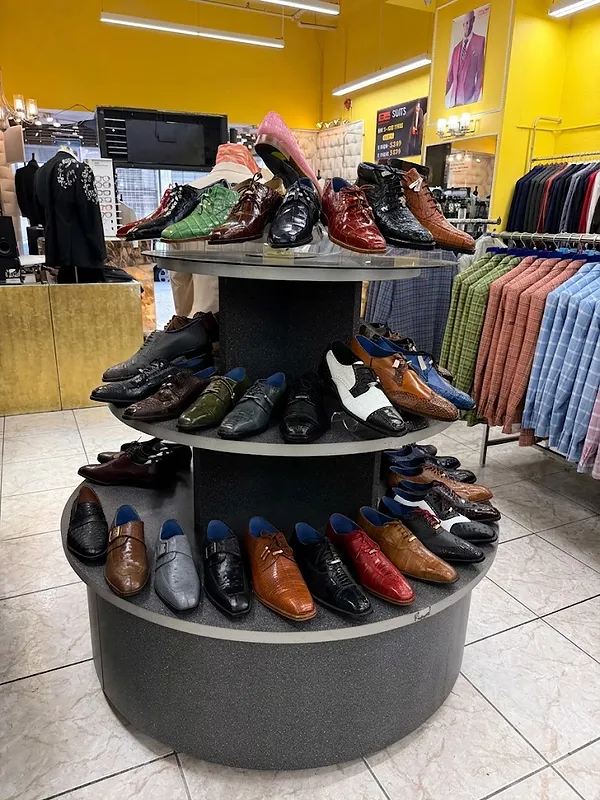 Three-tiered circular display of Italian dress shoes in the Paolo Cellini showroom with suit racks in the background