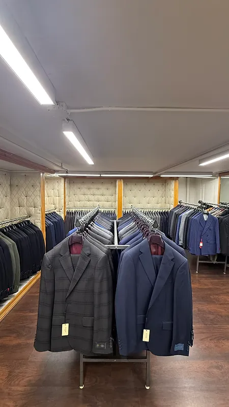 Two tailored suit jackets in the foreground with rows of suits receding toward a tufted wall at Paolo Cellini