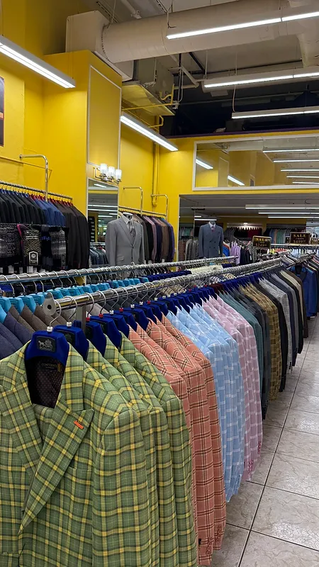 Rack of colorful plaid sport coats beside a mirrored wall and styled mannequins in the Paolo Cellini showroom