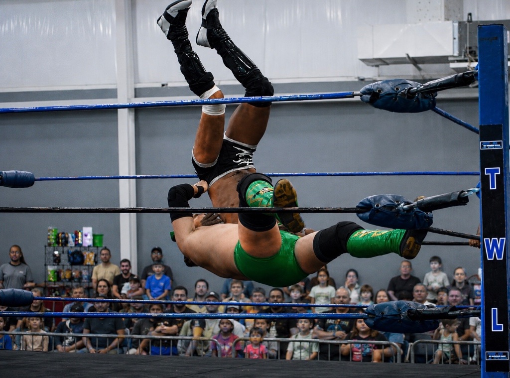 Texas wrestlers mid-air executing a finishing maneuver in front of a live crowd