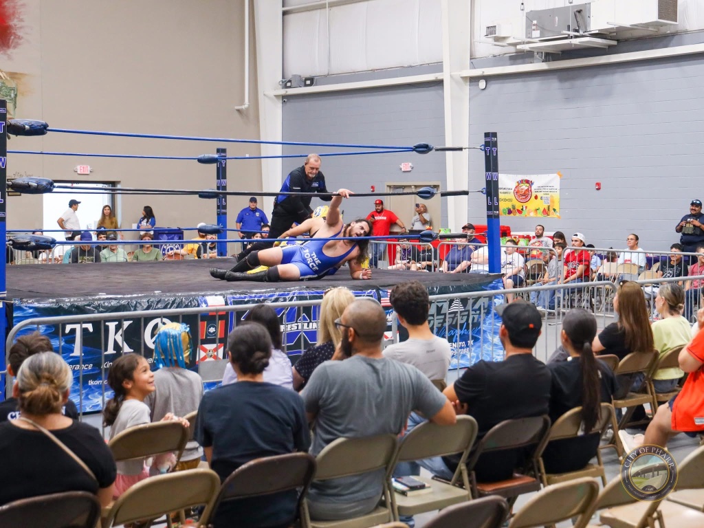A wrestler in 'The Force' singlet battles in the ring as the crowd watches on at Lucha Libros 2025.