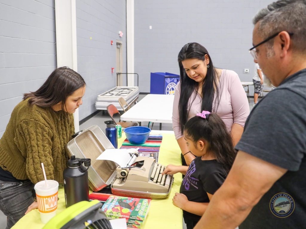 A young attendee tries out a vintage typewriter at the interactive book station featuring Rubén Degollado's 'The Family Izquierdo.'
