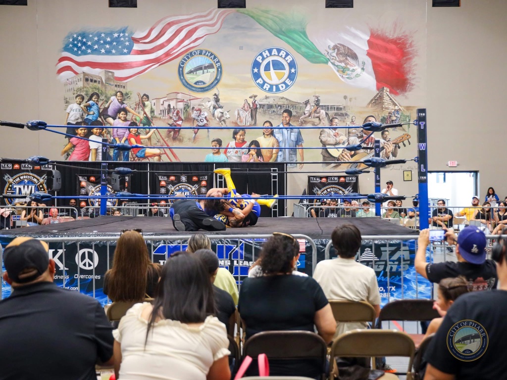 Live wrestling action unfolds in front of the Pharr Pride mural at Lucha Libros 2025.