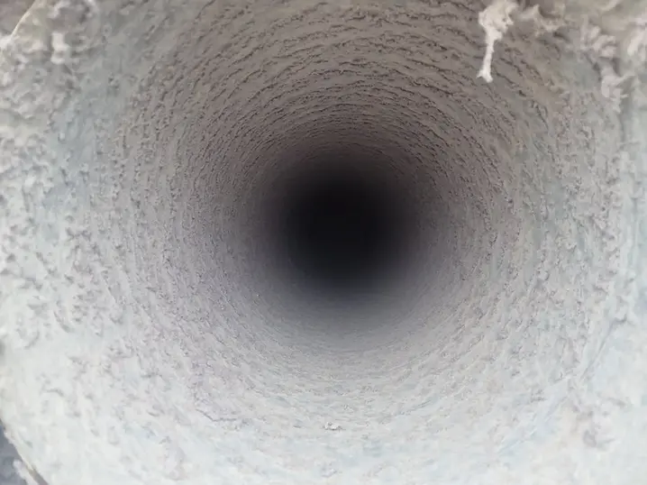 Lint and fibre build-up inside a tumble dryer extract duct before cleaning