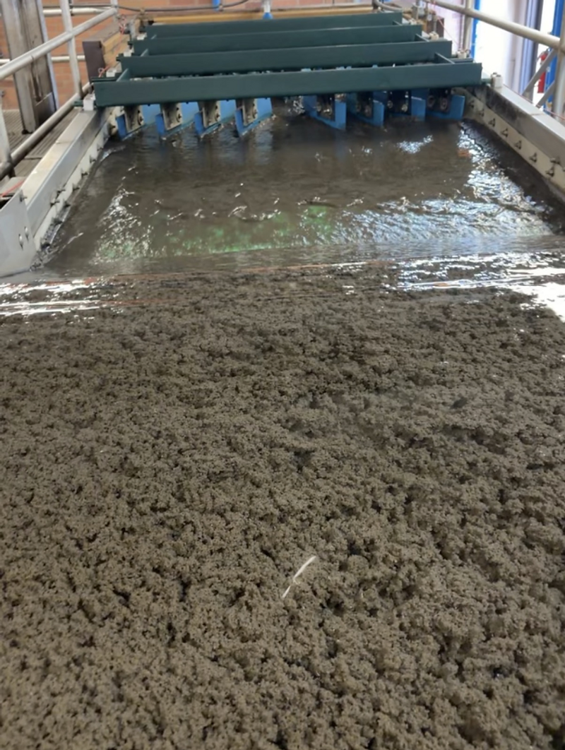 Industrial wastewater treatment tank channel with mechanical scraper