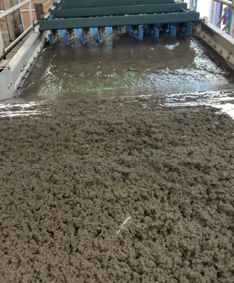 Industrial wastewater treatment tank channel with mechanical scraper