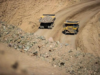 Haul trucks traveling a dirt road through an open-pit mine