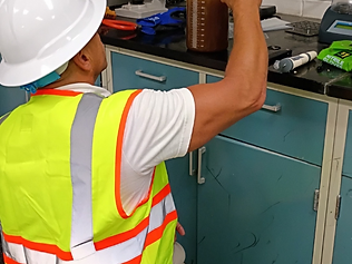 LaNova technician kneeling on the lab floor, reading a graduated cylinder during bench-scale settling trials