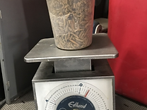 Portion-control scale weighing a container of tan fibrous recovered solids