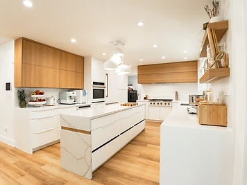 Kitchen with warm wood upper cabinets, white cabinetry, and a waterfall island