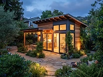 Detached ADU with wood siding and warm glowing windows in a lush East Bay backyard
