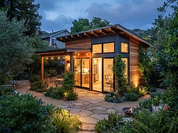 Detached ADU with wood siding and warm glowing windows in a lush East Bay backyard