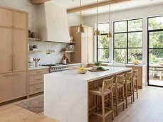 Remodeled modern kitchen with pale oak cabinetry and a large stone island
