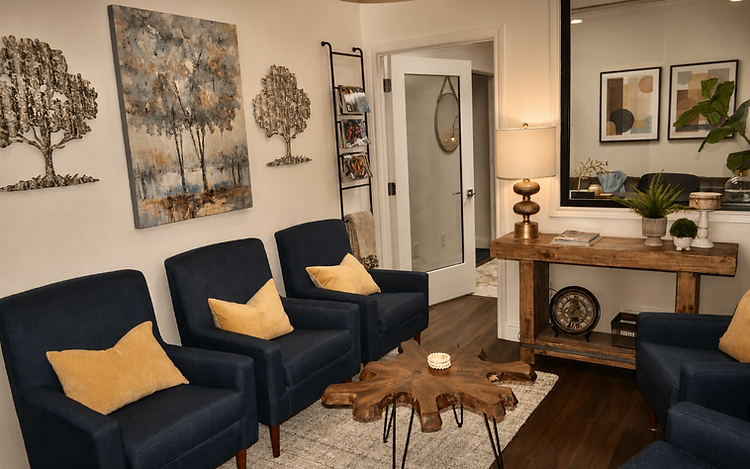 A polished ElmWorks office waiting area with navy armchairs, a rustic wood coffee table, and framed art