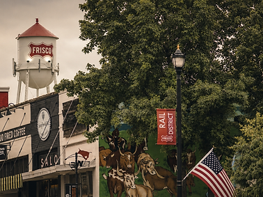 Street-level view of Frisco's Rail District with historic storefronts and the Frisco water tower