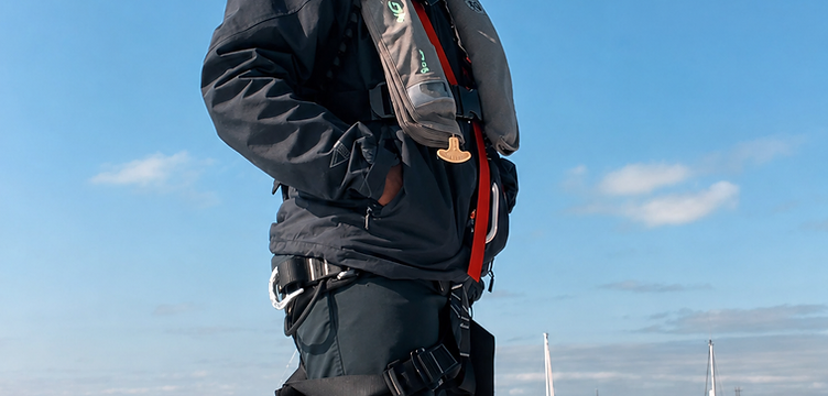 A maritime professional in safety gear standing on a vessel deck at a Caribbean marina