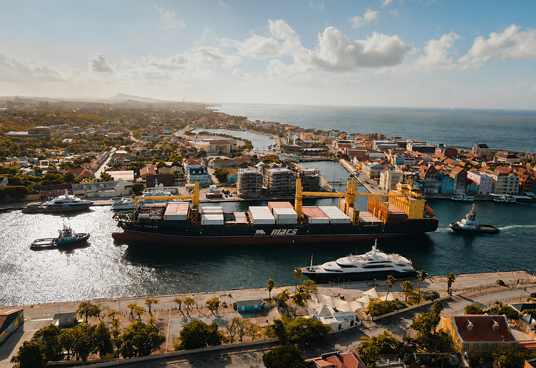 Aerial view of a cargo vessel with tugboats navigating a Caribbean harbour entrance