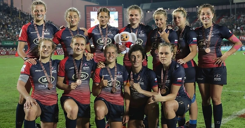 Women's rugby team celebrating with medals in custom kit