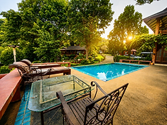 Poolside Relaxation in Nature A peaceful poolside setting surrounded by lush gardens, with warm western light creating a relaxing natural atmosphere.