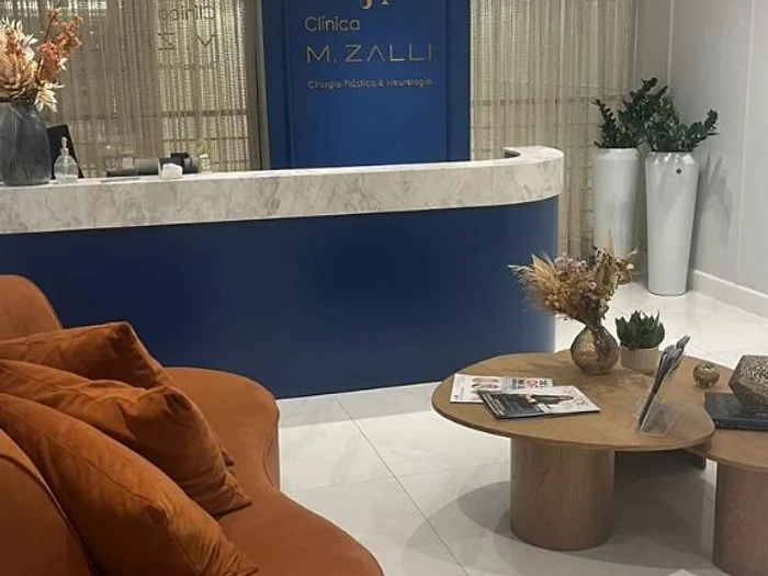 Recepção do consultório do Dr. Marcelo Zalli em Balneário Camboriú — clínica neurologista com ambiente acolhedor e moderno, sofá em terracota e balcão em mármore