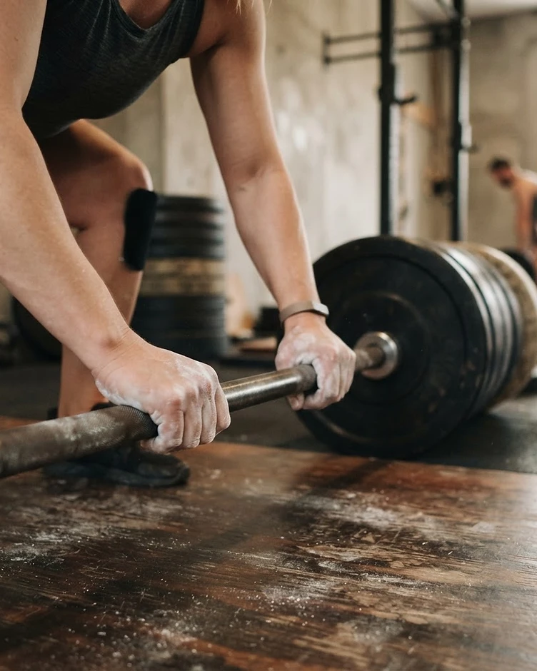 A close-up of hands gripping a loaded barbell on a platform