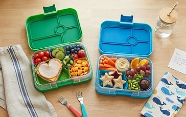 Colorful healthy kid-friendly lunch boxes with fruits, vegetables and snacks on a clean kitchen counter