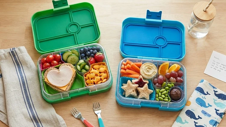 Colorful healthy kid-friendly lunch boxes with fruits, vegetables and snacks on a clean kitchen counter
