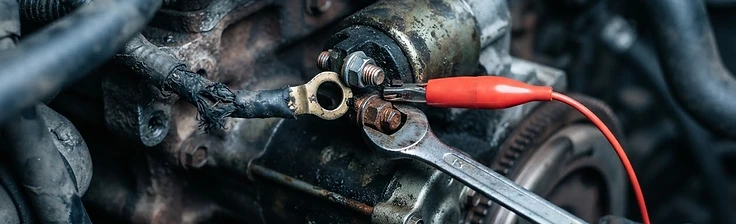 Starter motor and its electrical supply cable being inspected with a voltmeter lead attached