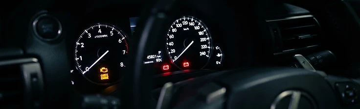 Car instrument cluster at night with battery and engine management warning lights illuminated