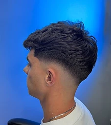 Wavy textured top with mid-skin fade against blue backdrop