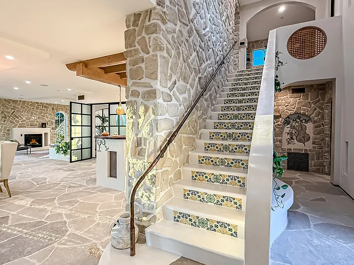 The tiled stair rising past a stone wall to a round screened opening, at Mintcello in Malibu, by Apel Design