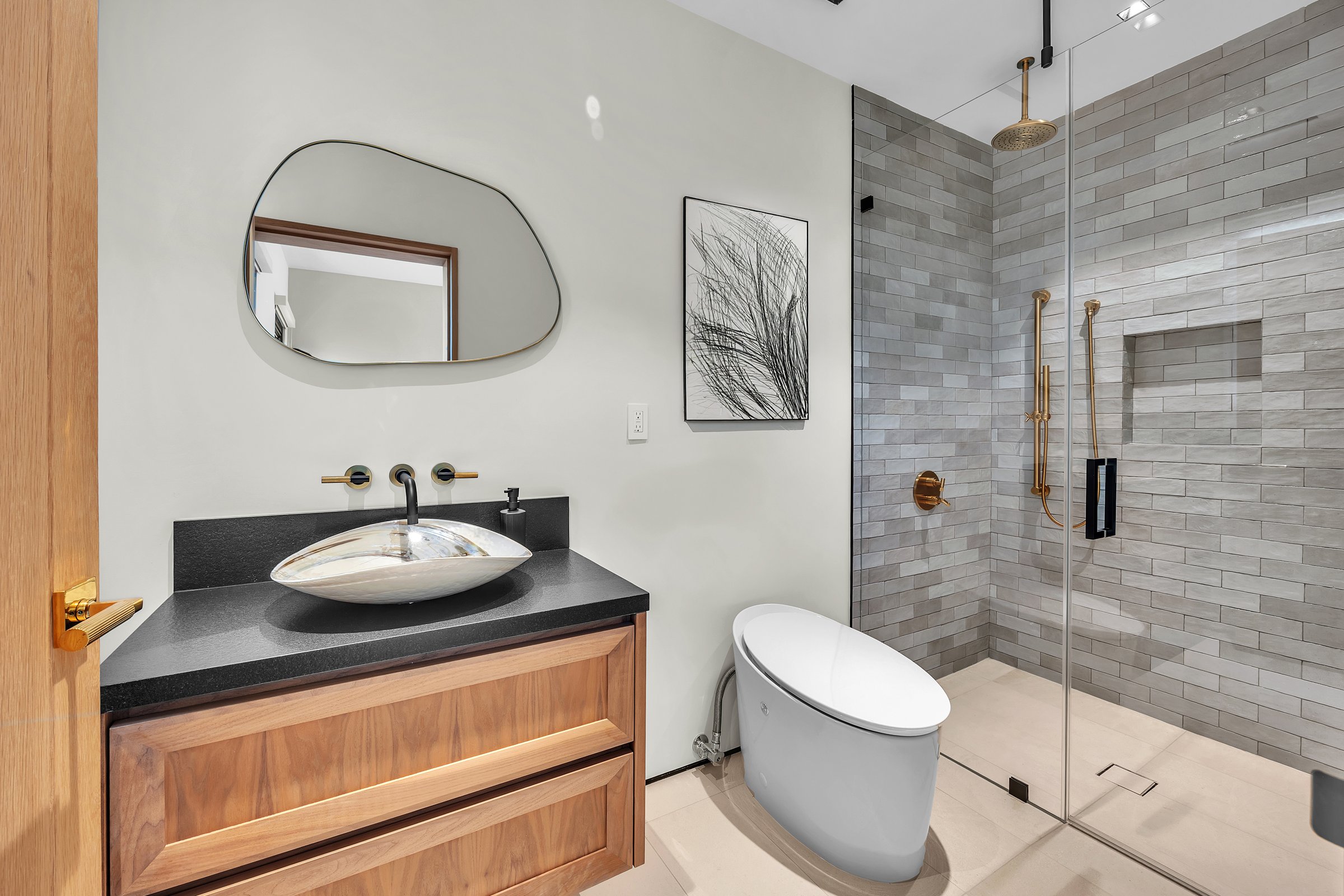 A guest bath in warm wood, black stone and grey glazed tile, Merritt Estate in Malibu by Apel Design