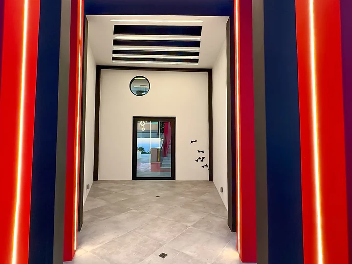 A corridor framed by nested red and blue portals edged in light, at The Aviator in Malibu, by Apel Design