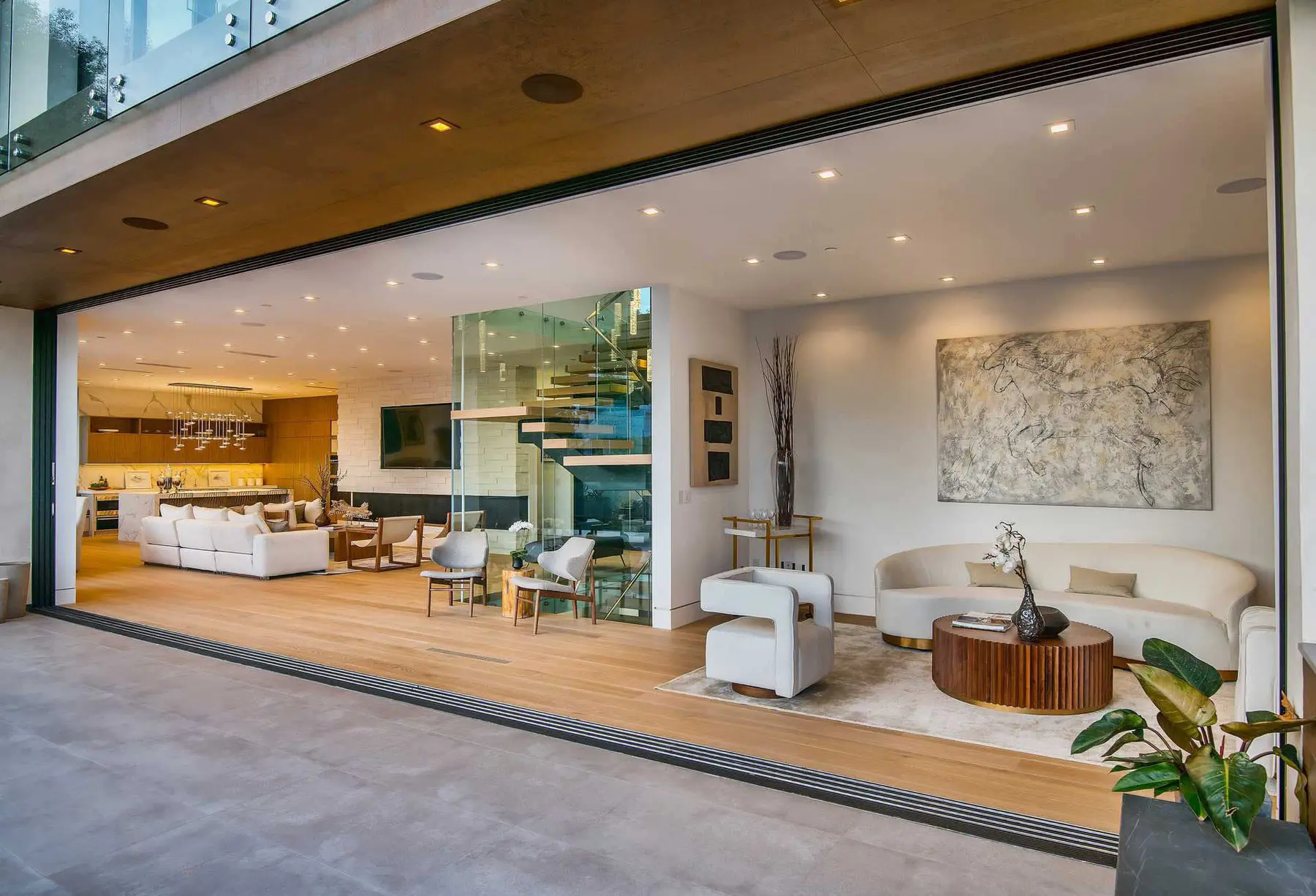 Living room with a full glass wall slid open to a covered terrace, an interior by Apel Design