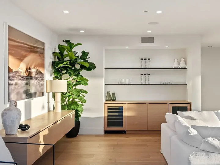 A wood console with a lamp and vases below a large wave photograph, an interior by Apel Design