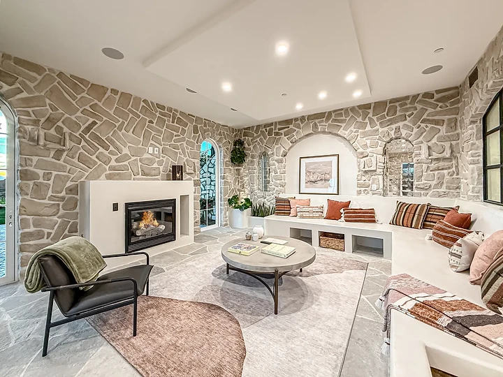 Striped cushions on a curved banquette under stone walls and arched niches, at Mintcello in Malibu, by Apel Design