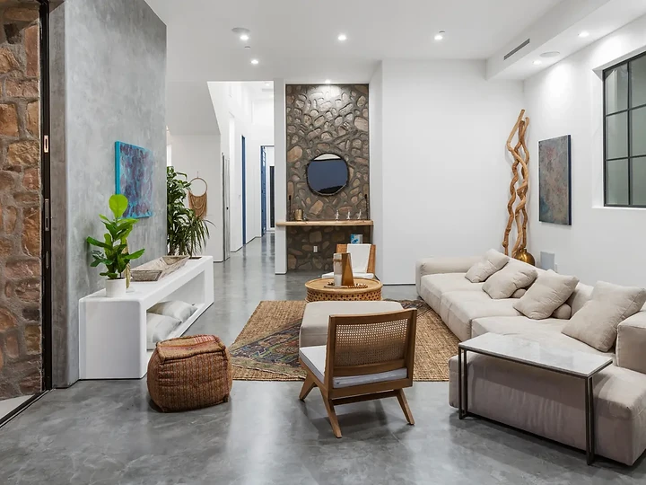 A concrete-floored sitting area with woven-back chairs and a driftwood sculpture, at Maliview in the Malibu Mountains, by Apel Design