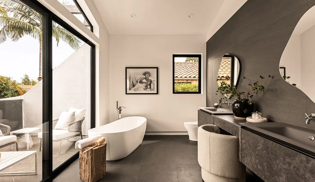 The primary bath, with a freestanding tub beside a glass wall to a private terrace, La Jolla North in West Hollywood by Apel Design