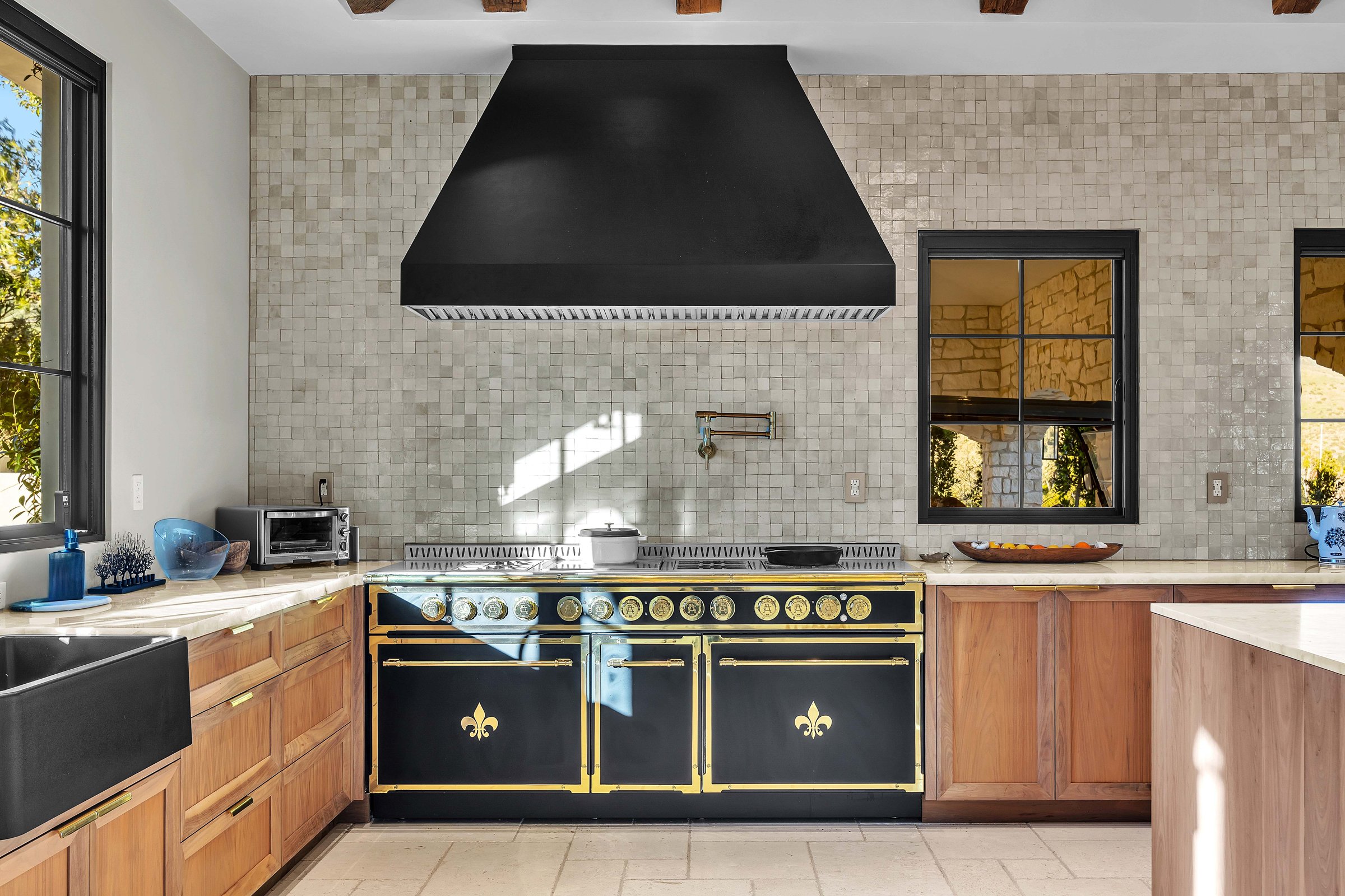 The range under a black hood, set against glazed tile, Merritt Estate in Malibu by Apel Design