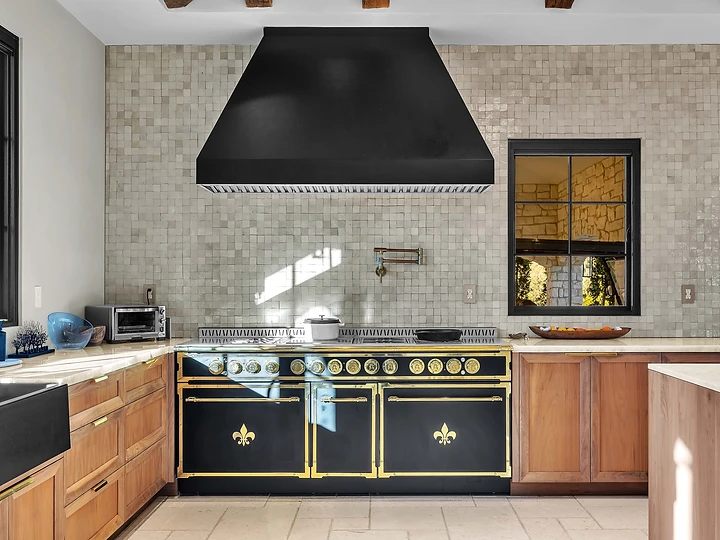 Black range under a black hood against glazed tile, at Merritt Estate in Malibu, by Apel Design