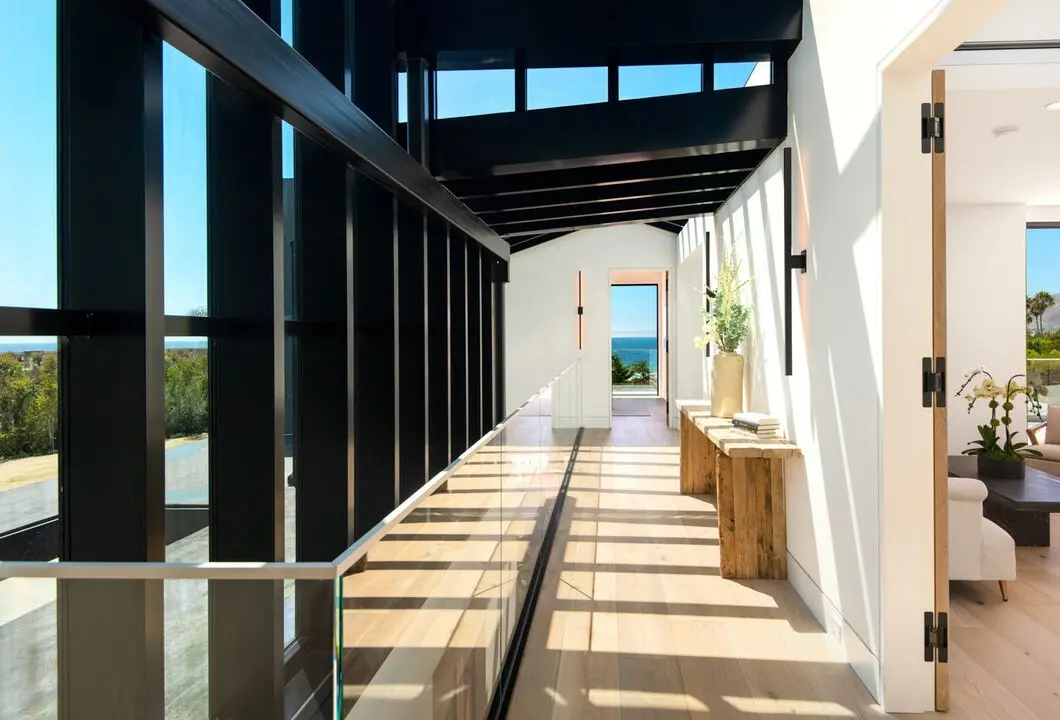 Glass-railed gallery hallway with ocean views in an Apel Design interior